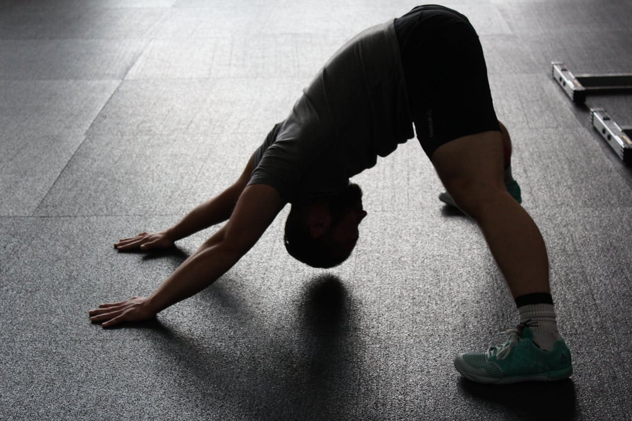 Stretch Your Way to Strength: How Simple Movements Unlock Resilience and Well-Being man stretching at the gym
